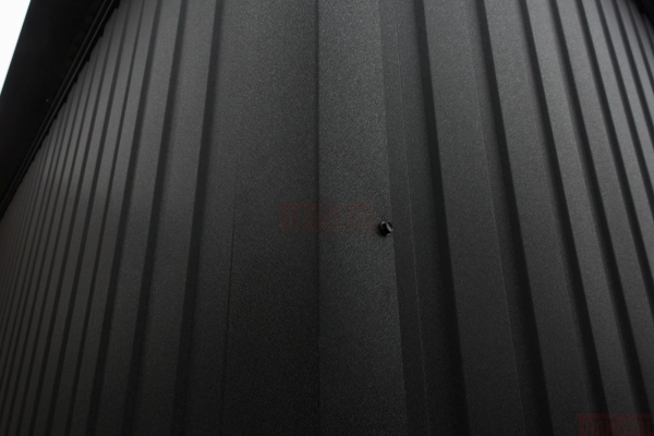 Angled close-up of matte black corrugated metal siding with a visible wall screw.