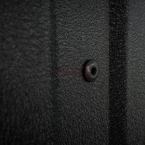 Close-up of a matte black rivet on textured metal siding.