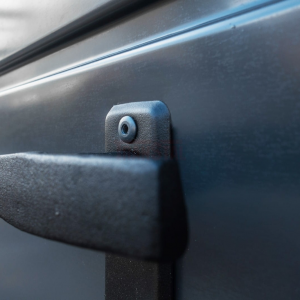 Close-up of a black textured metal handle and mounting screw on a graphite-colored garage door.