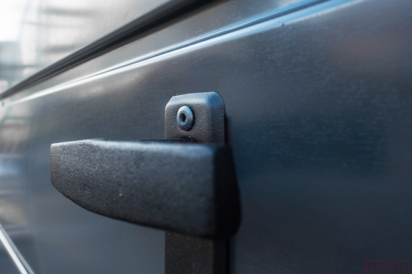 Close-up of a black textured metal handle and mounting screw on a graphite-colored garage door.