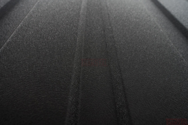 Close-up of matte black corrugated metal siding with a textured finish.